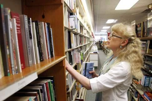 Jan Weissmiller looks through a shelf of books at the Prairie Lights Bookstore