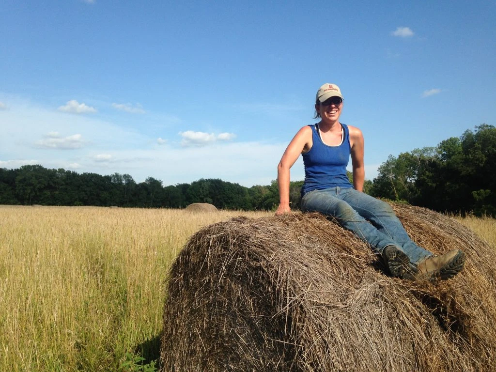 Kate Edwards sits on a hay bale at Wild Woods Farm